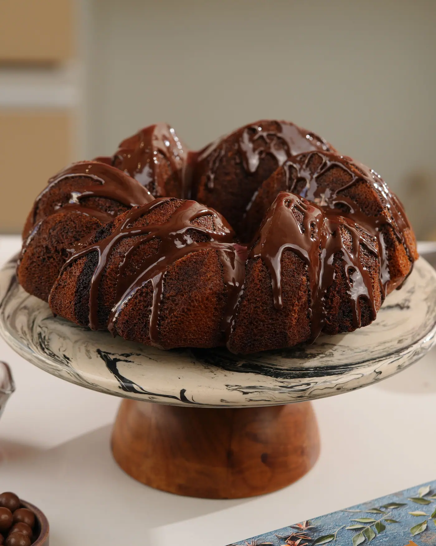 Chocolate-glazed bundt cake on a cake stand, one of the desserts on her menu